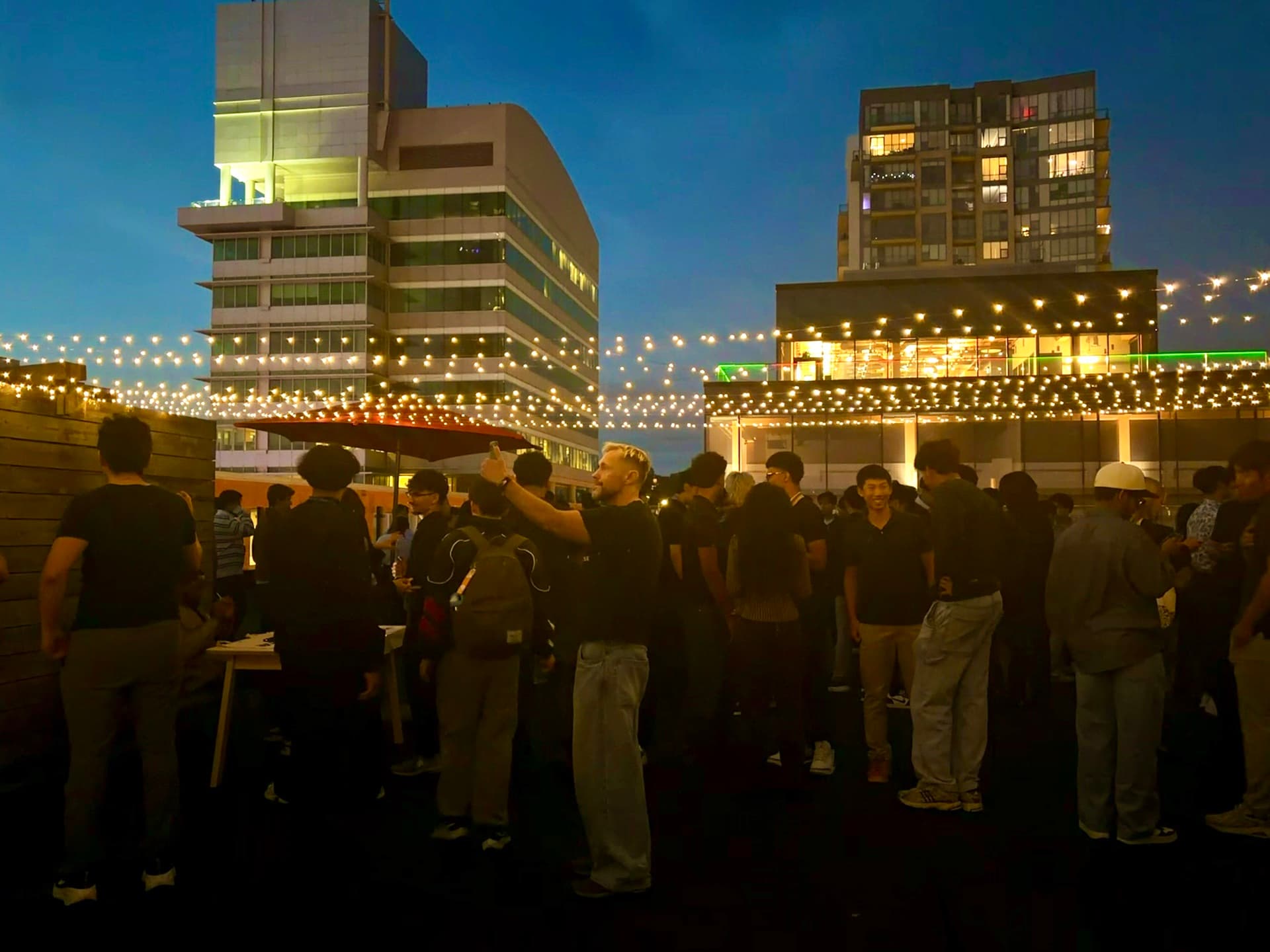 Attendees mingling beneath string lights at an outdoor event